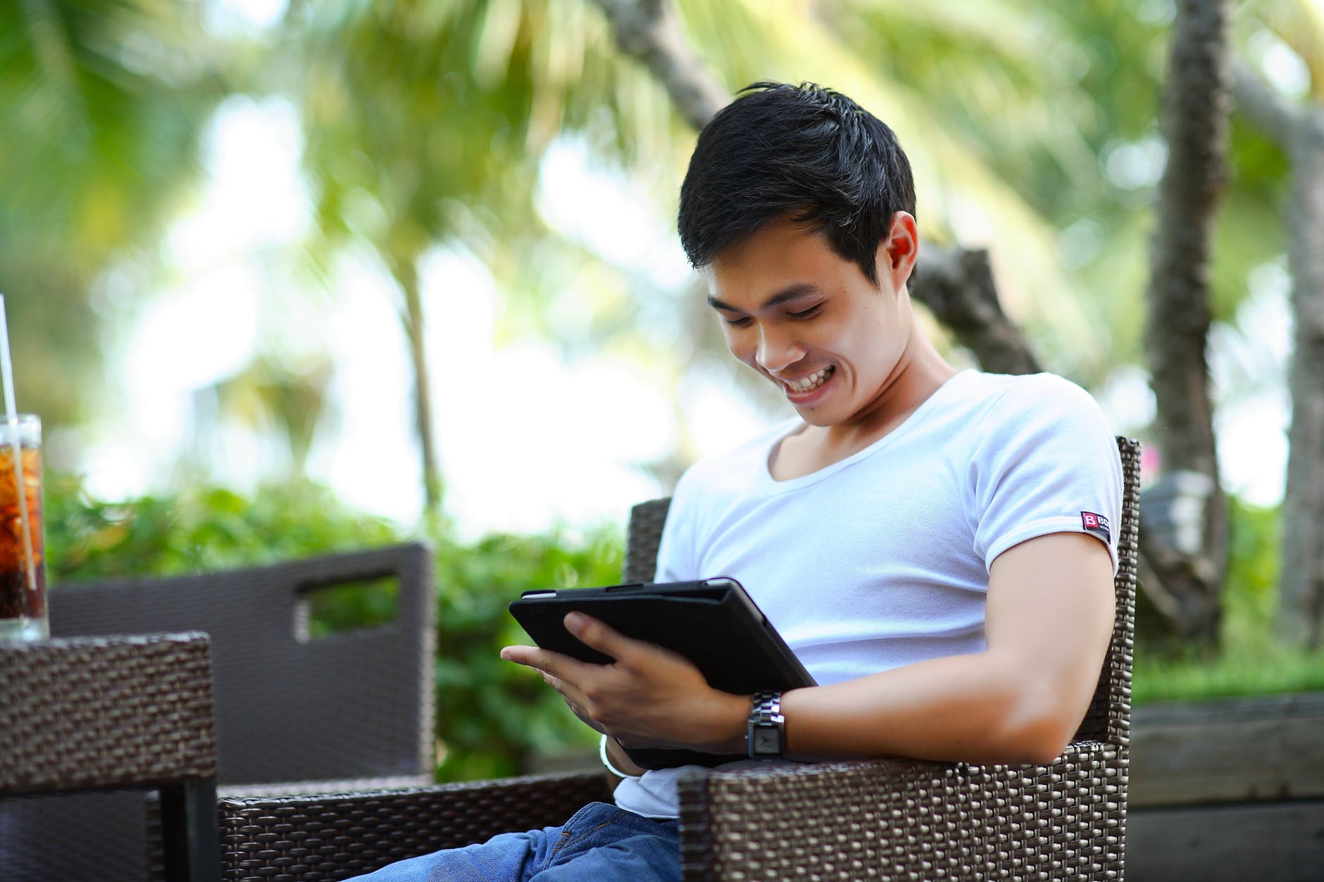 man sitting outside smiling at an iPad