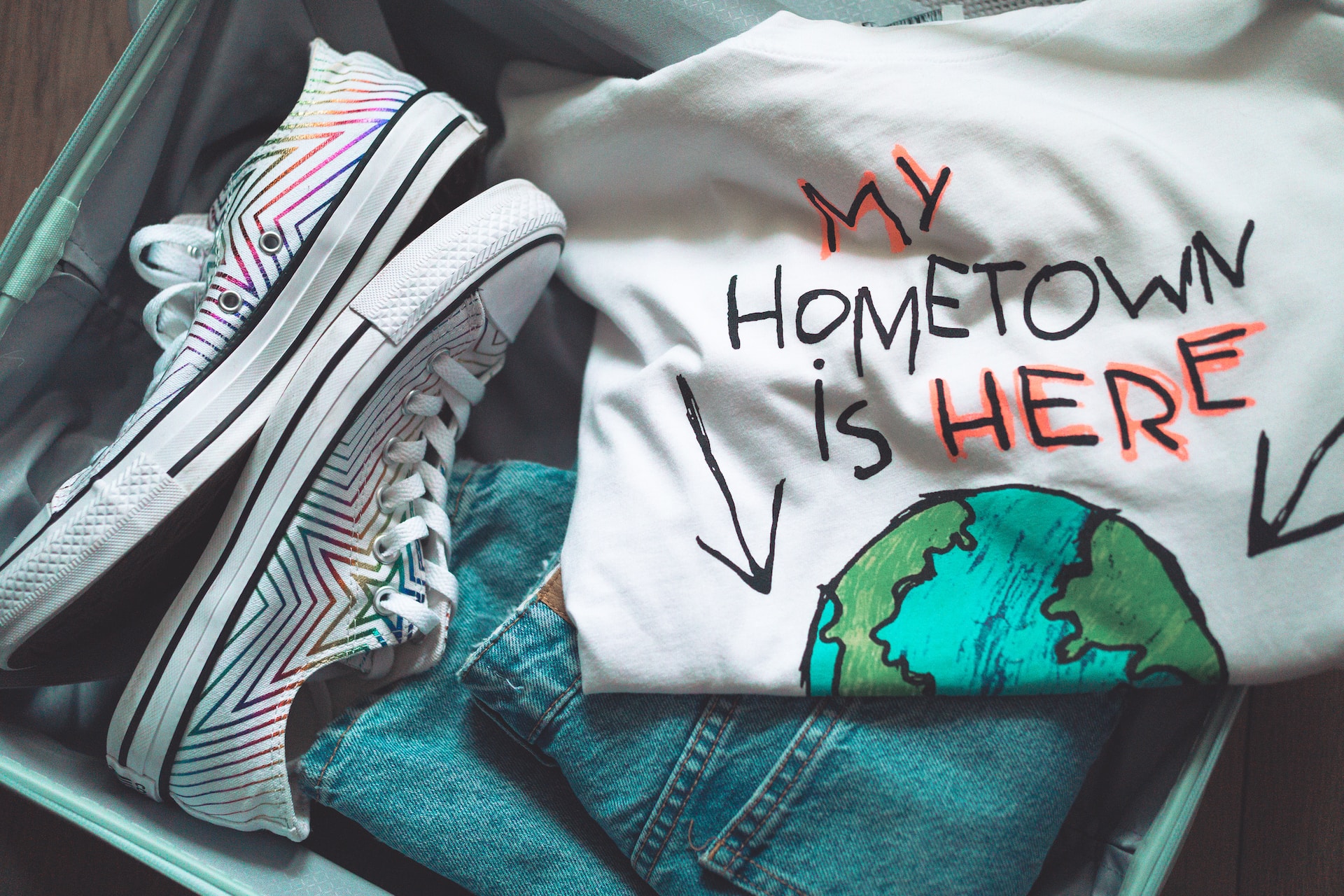 t-shirt in suitcase with image of globe and the words my hometown is here with arrows pointing to the ocean
