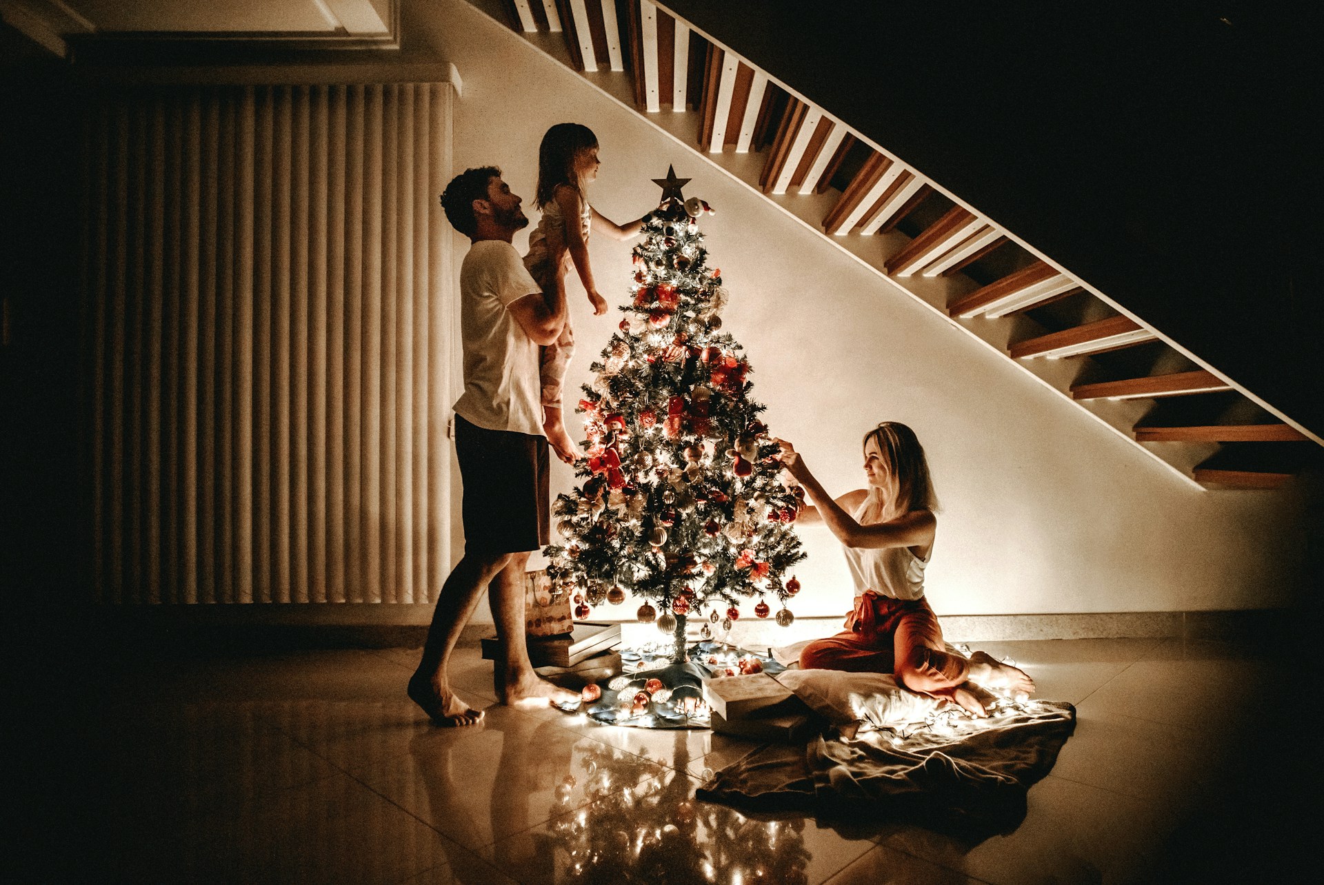 parents and a young child decorating a Christmas tree