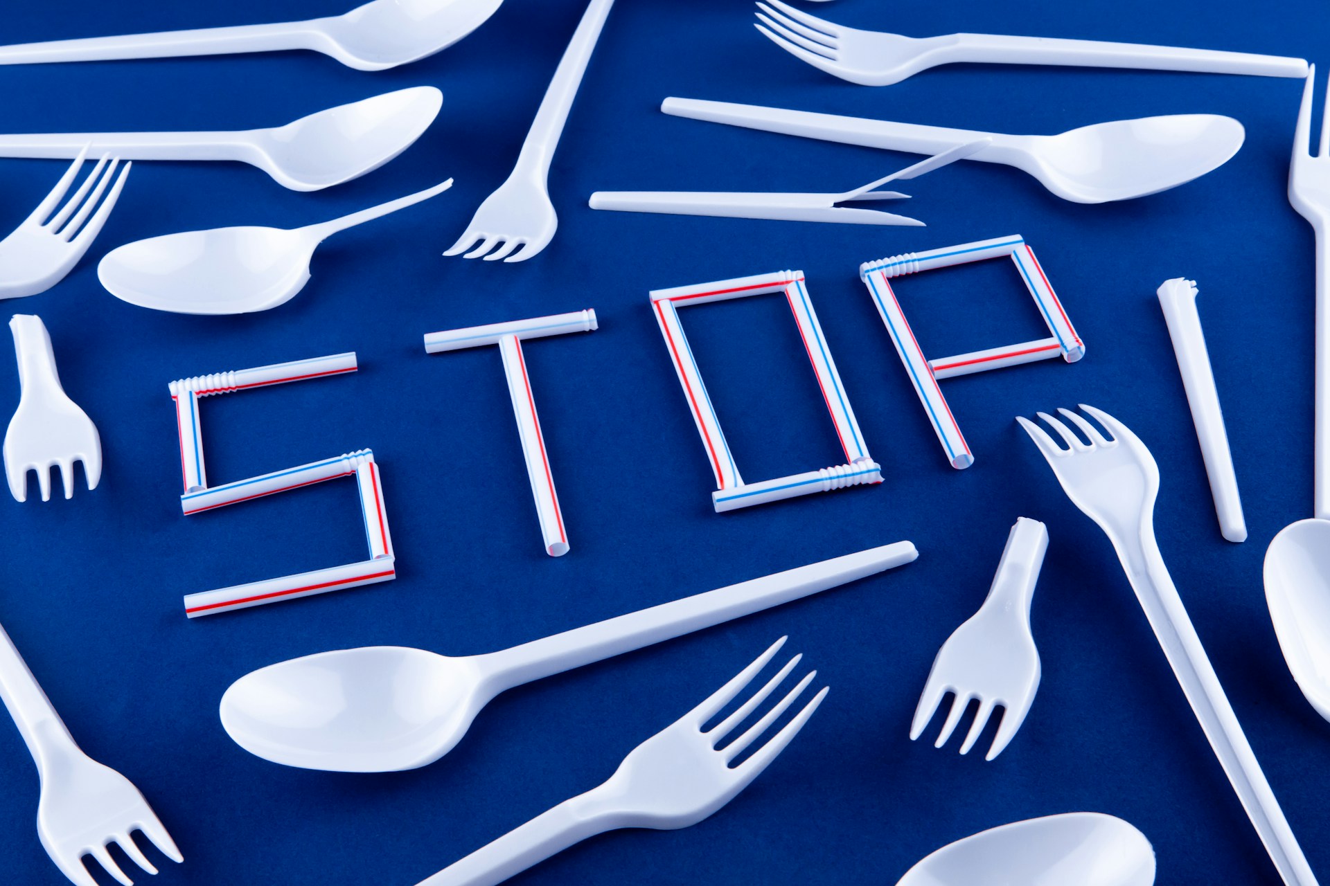 the word 'stop' spelt out by plastic straws surrounded by plastic cutlery