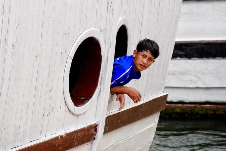 young seafarer leaning through porthole 