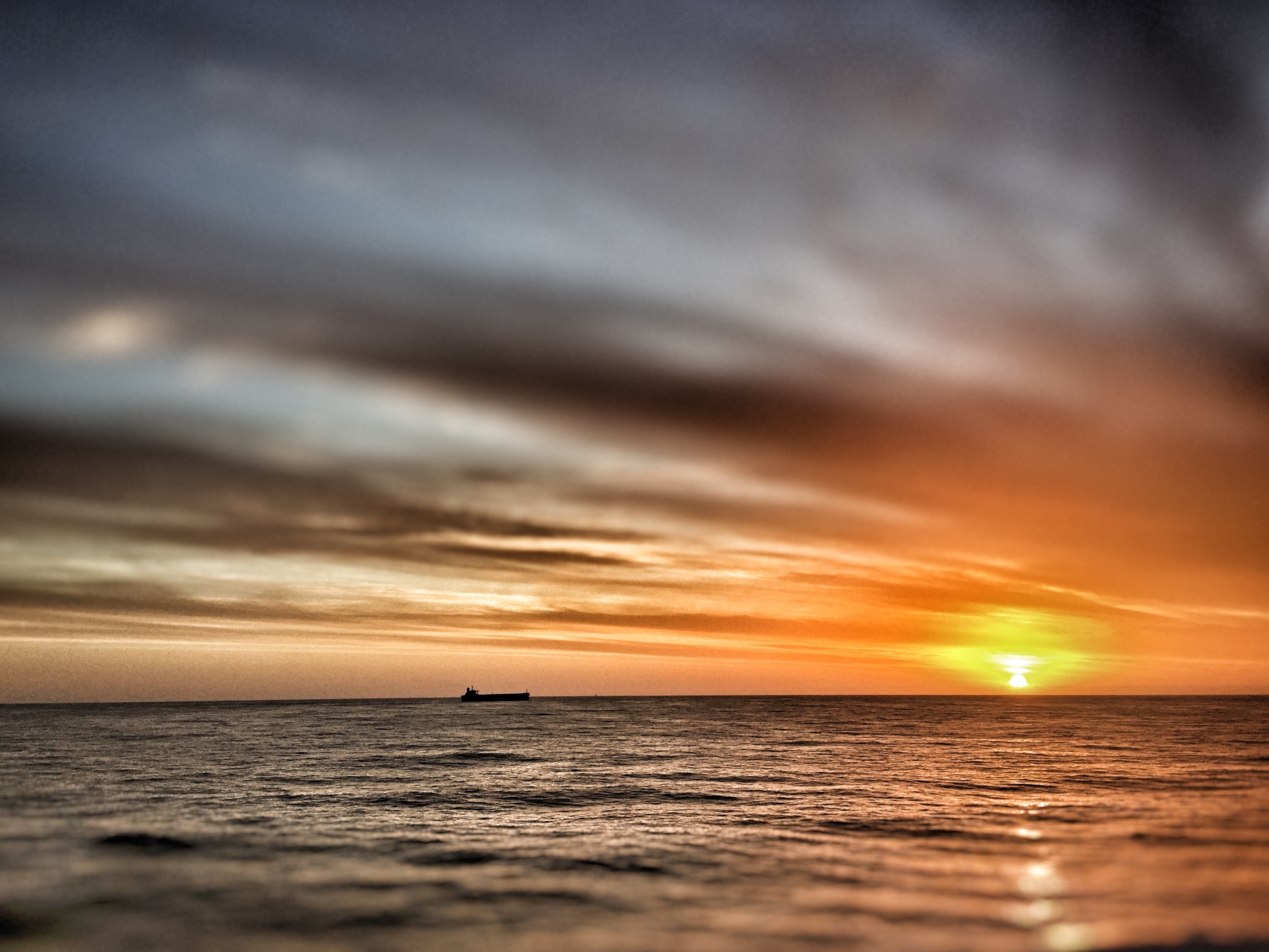 the silhouette of a vessel at sunset