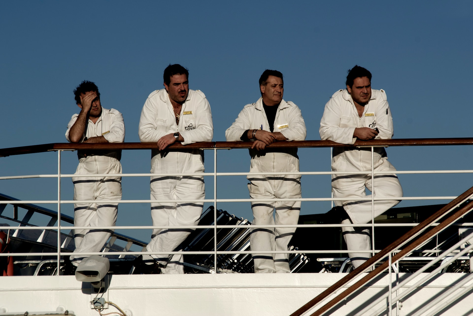 Four seafarers leaning on the rail of a deck