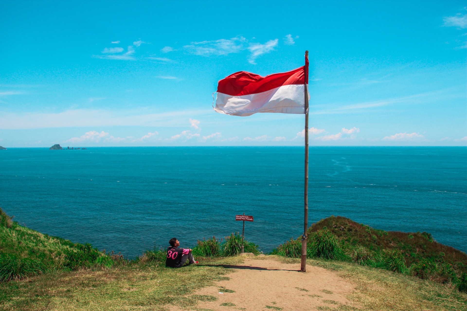 The Indonesian flag flying with the ocean in the background