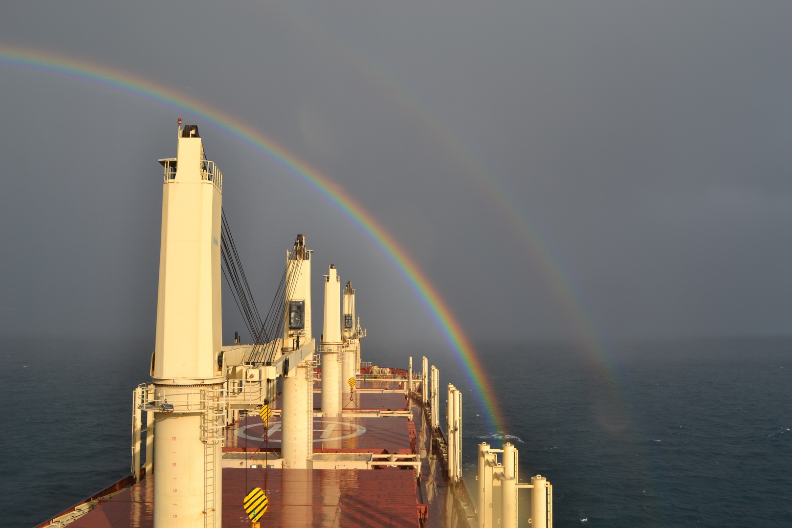 a bulk carrier sailing towards a rainbow