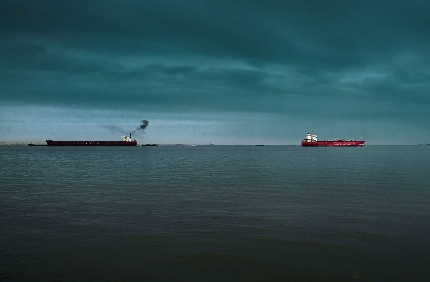 two oil tankers at sea under a stormy sky