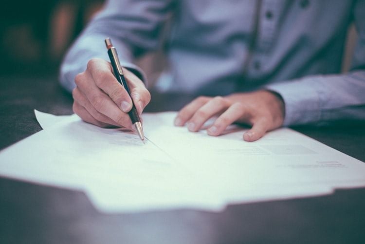 man writing on paper as if writing a seafarer resume