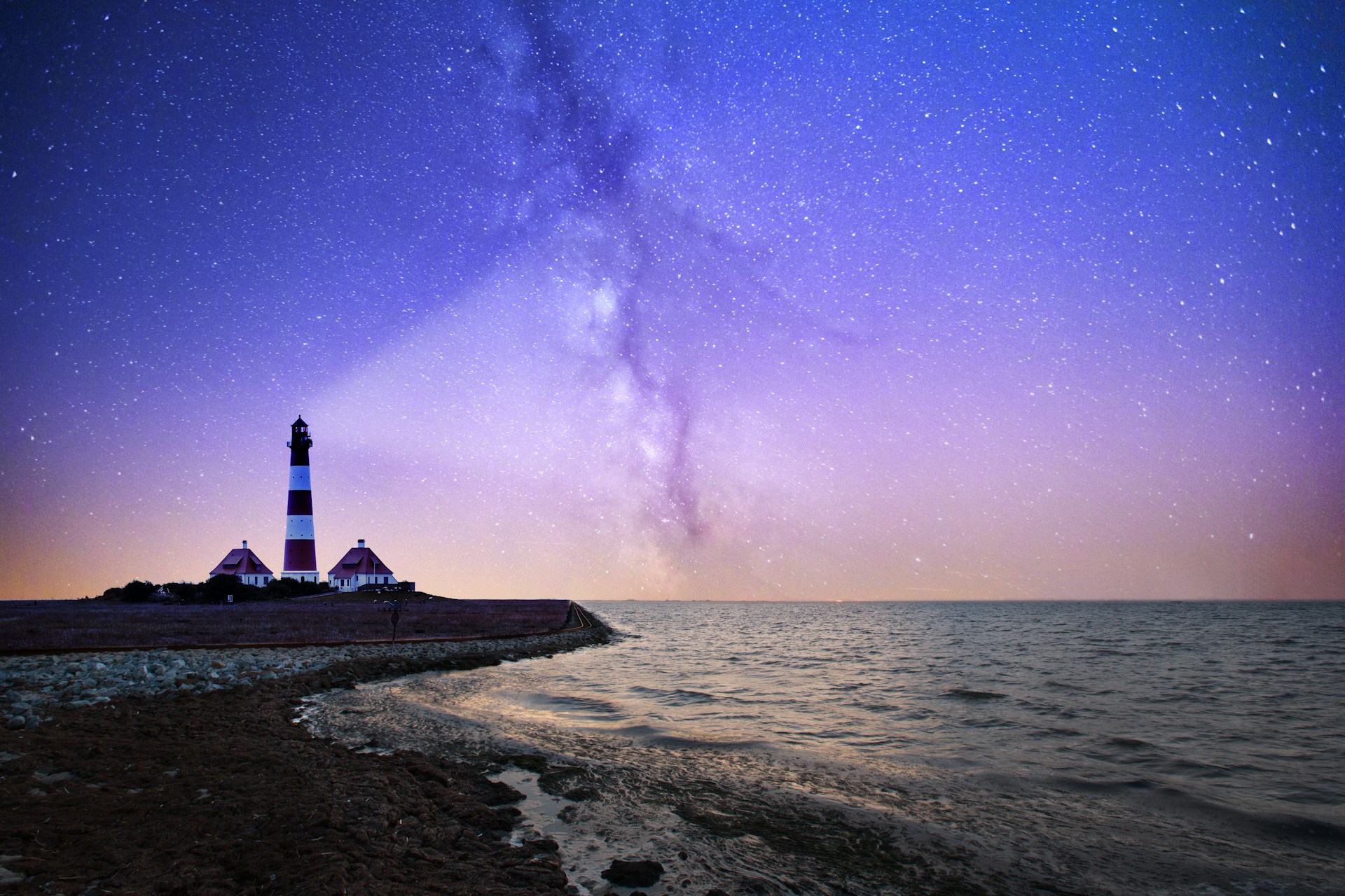 A lighthouse casting its beacon across a starry sky