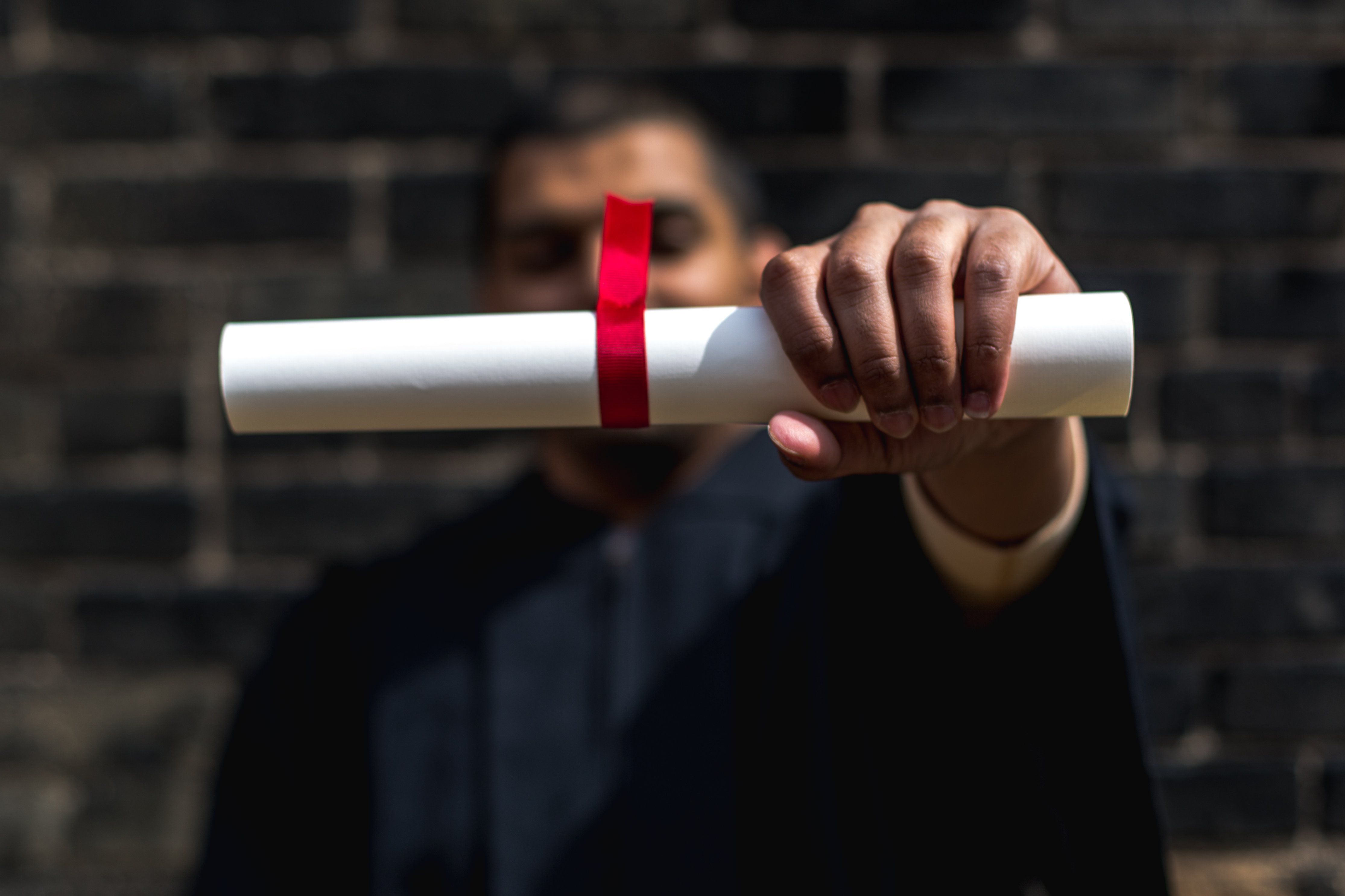 a graduate holding out his diploma