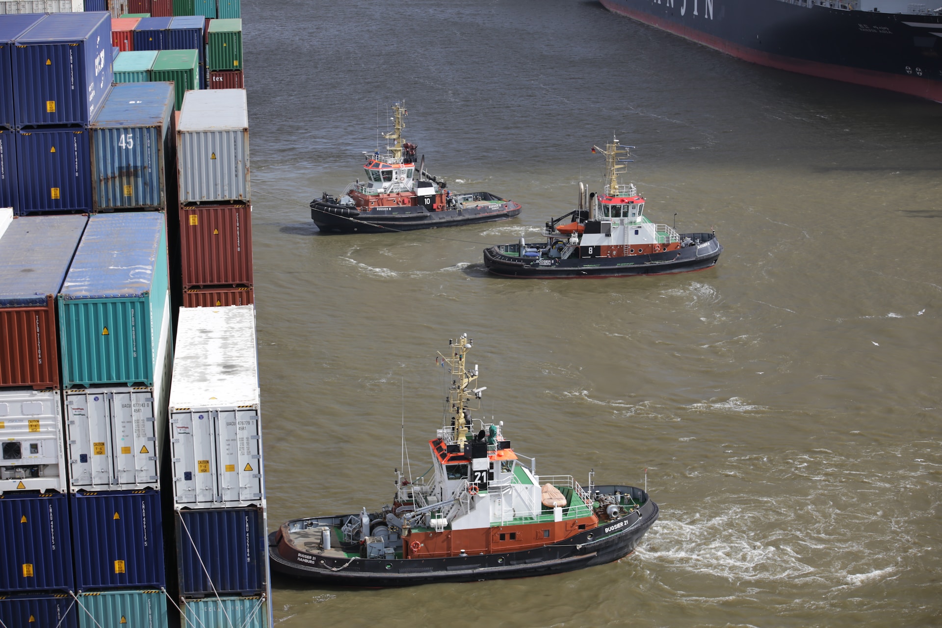 Three tugboats and a container ship