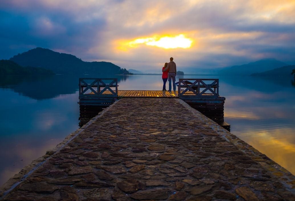 couple standing on dock looking at sea