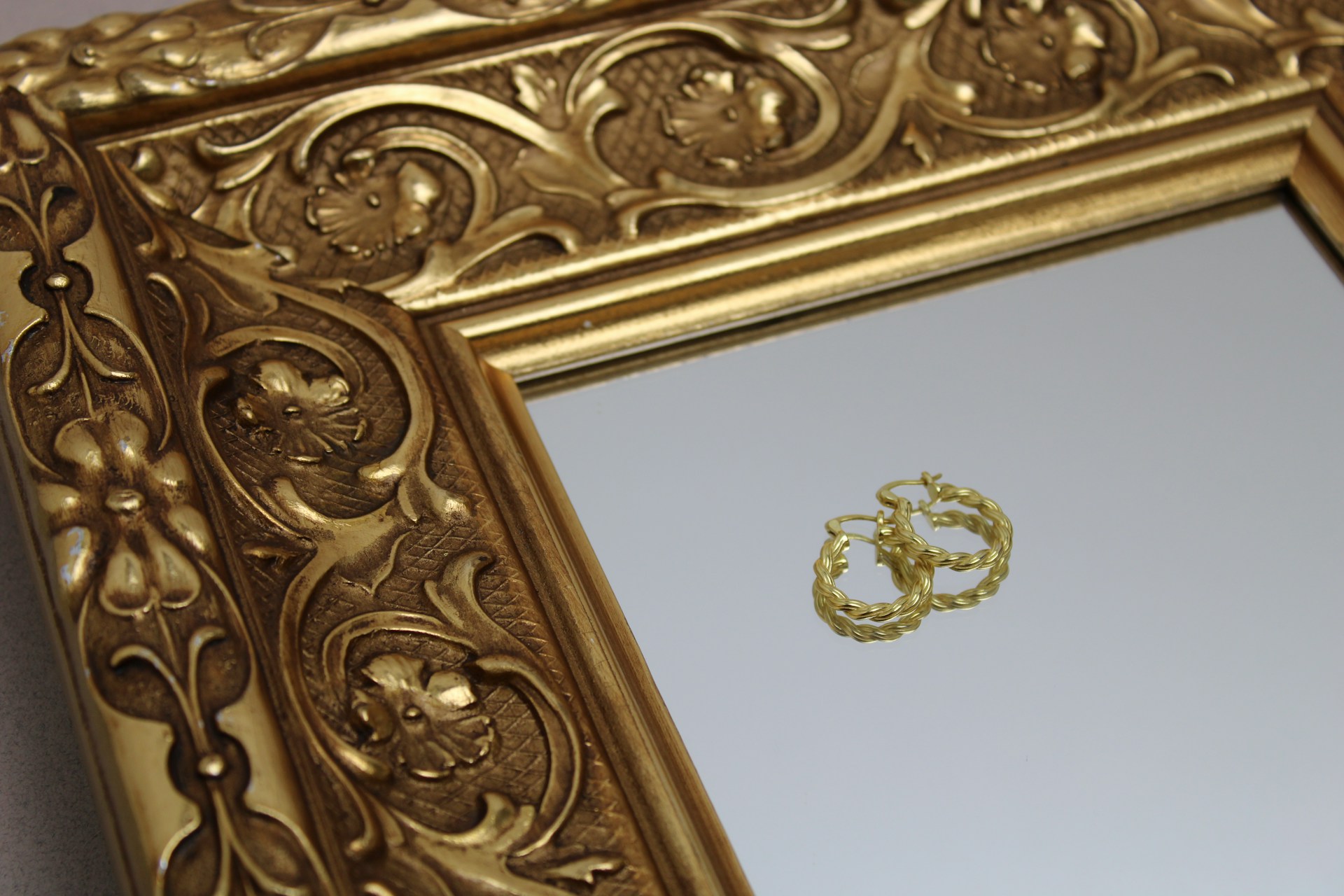 gold hooped earrings on an ornate mirror