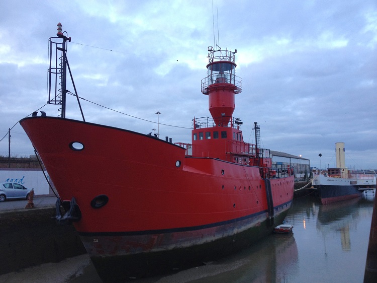 A large red lightship in a harbor