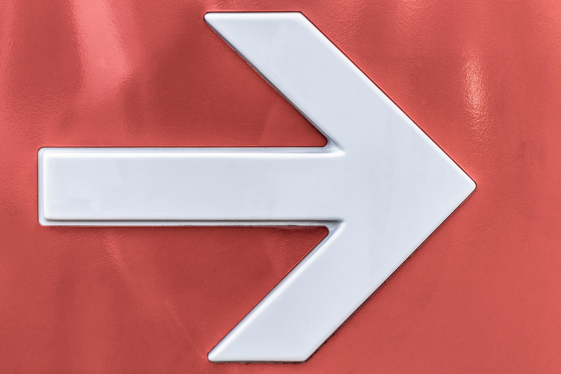 a white arrow on a red background pointing forward