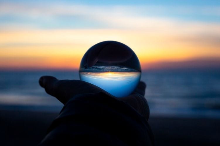 hand holding crystal ball in front of ocean