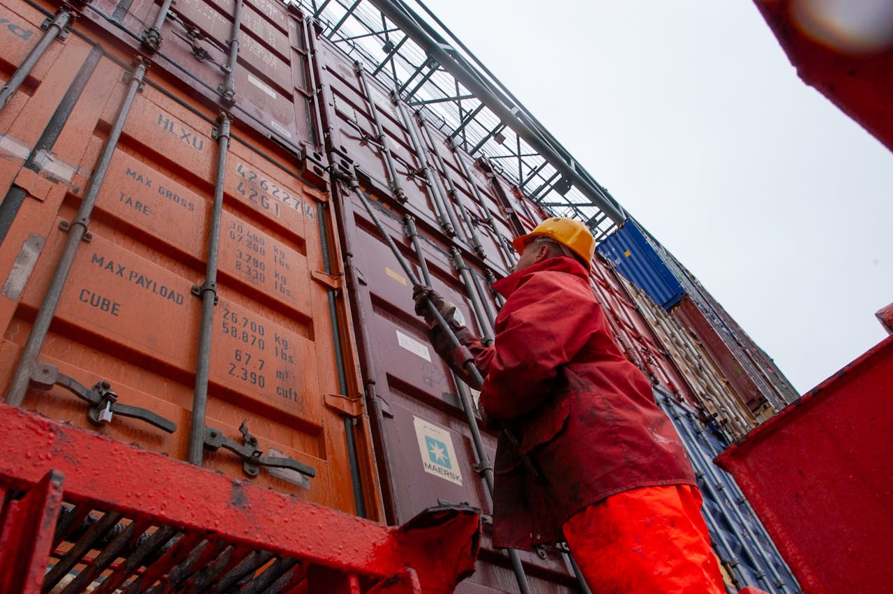 a dock worker climbing up the side of a shipping container