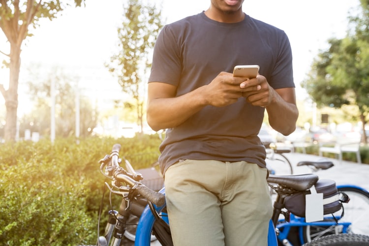 a man leaning on a parked bicycle using his phone