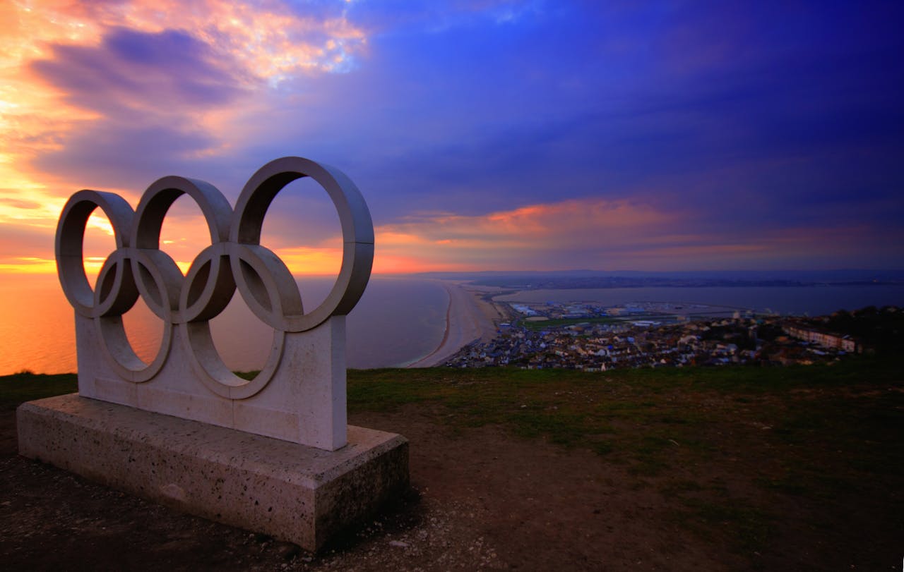 a sculpture of the Olympic rings on a cliff at sunset