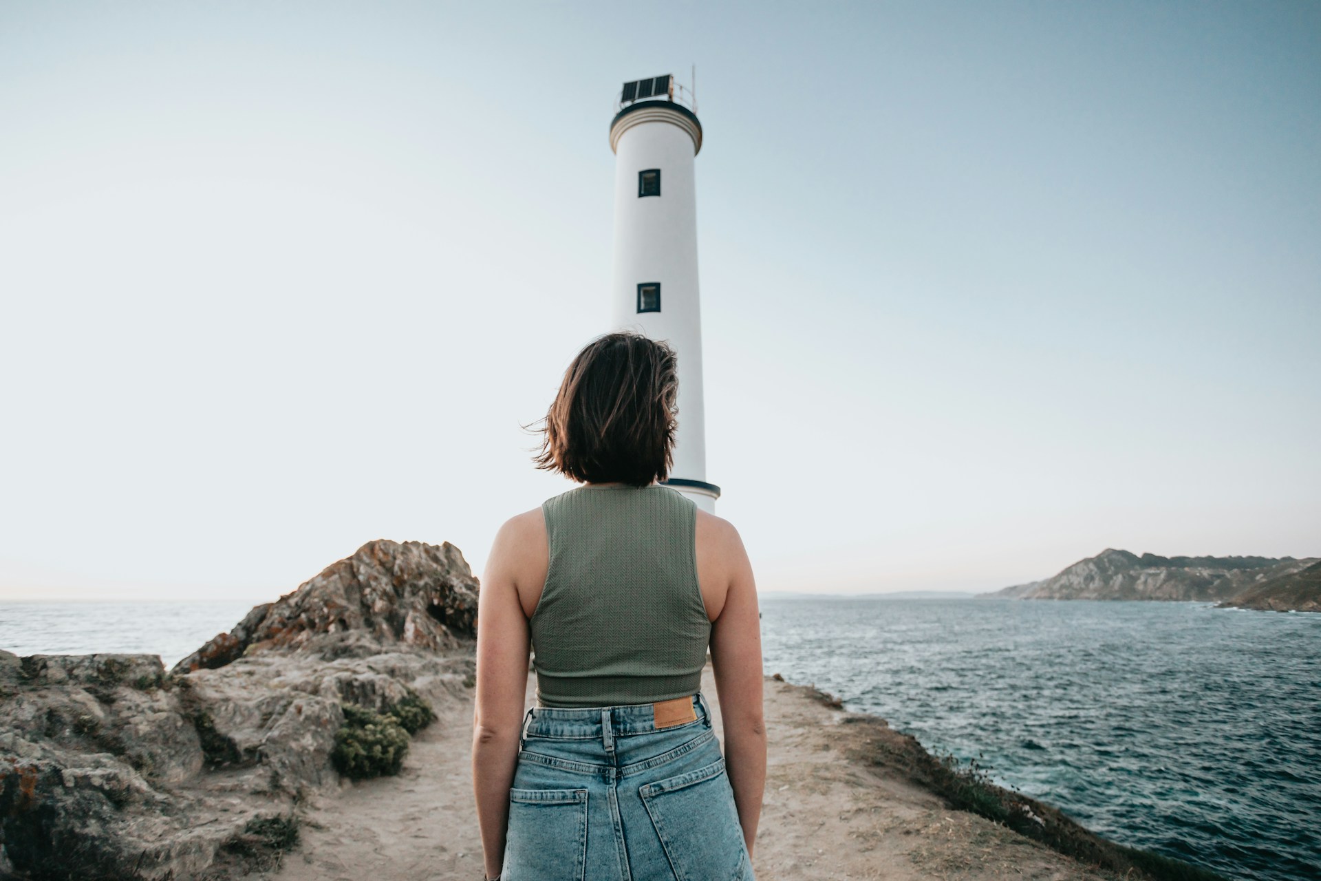 a woman standing in front of a lighthouse