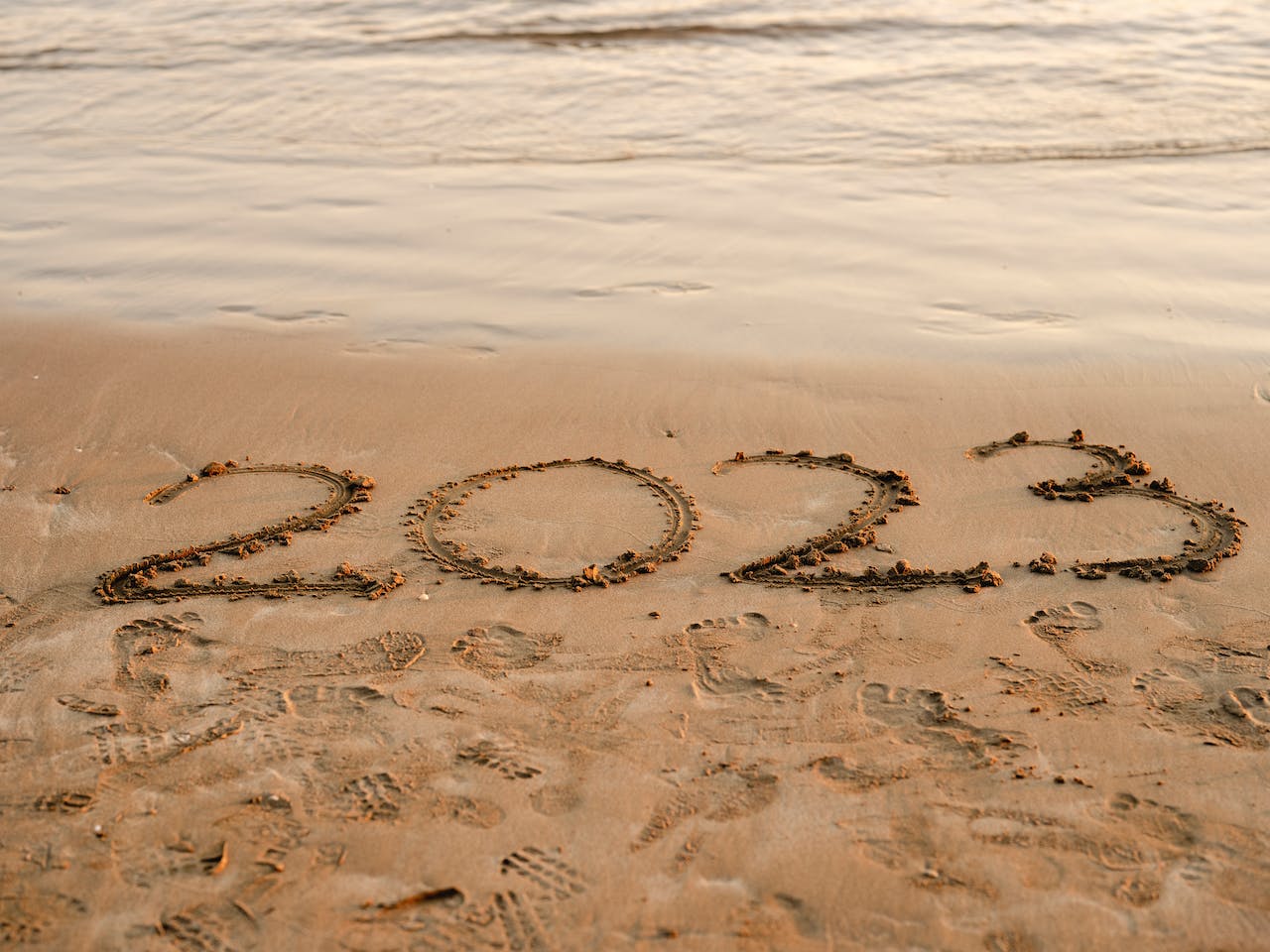 2023 written on a sandy beach