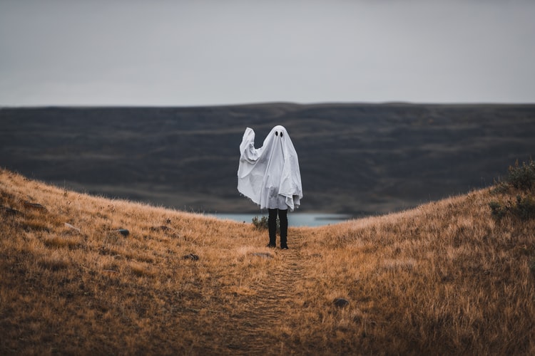 person in a ghost costume waving goodbye