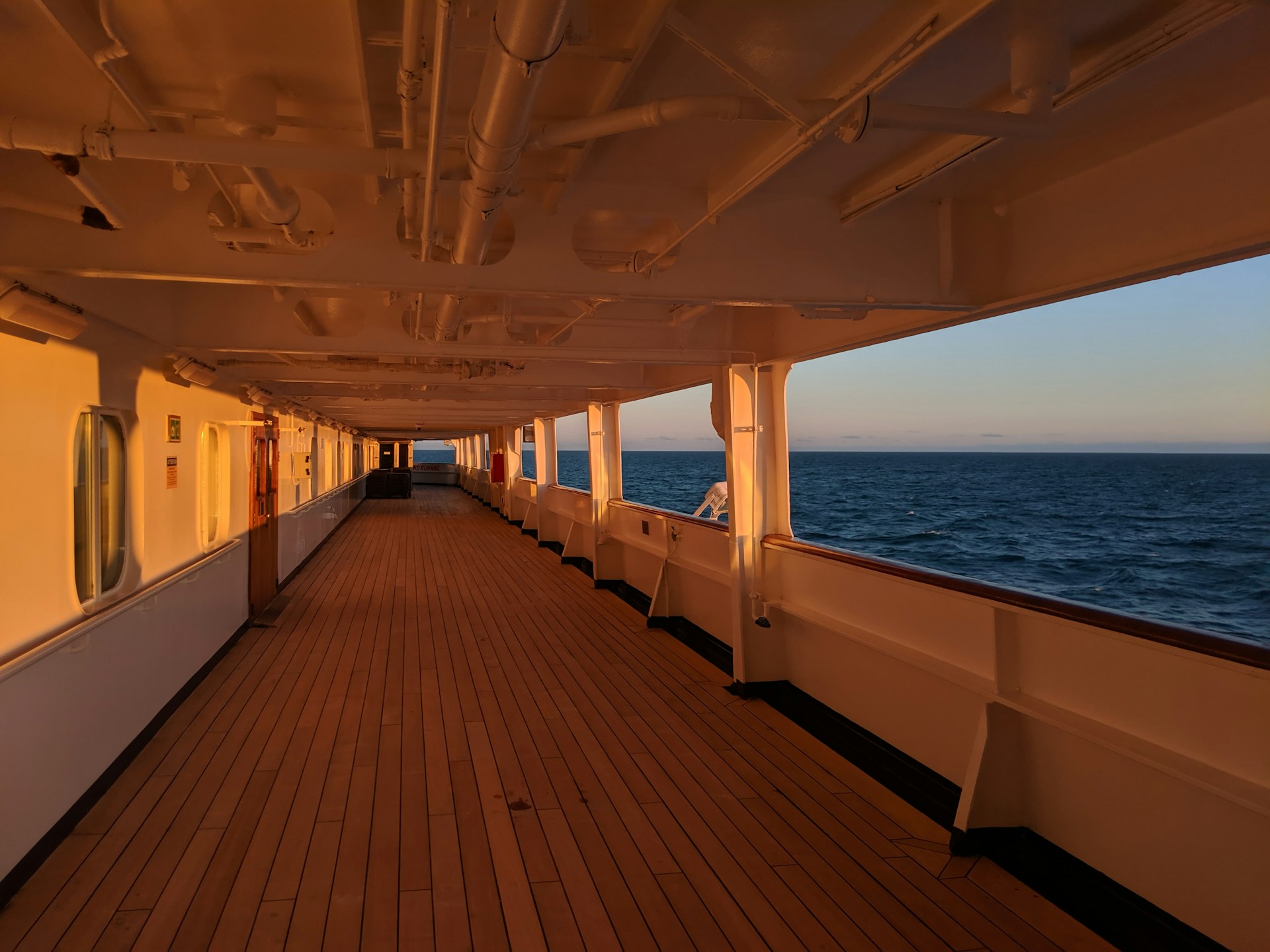 the sun setting on a walkway on a cruise ship