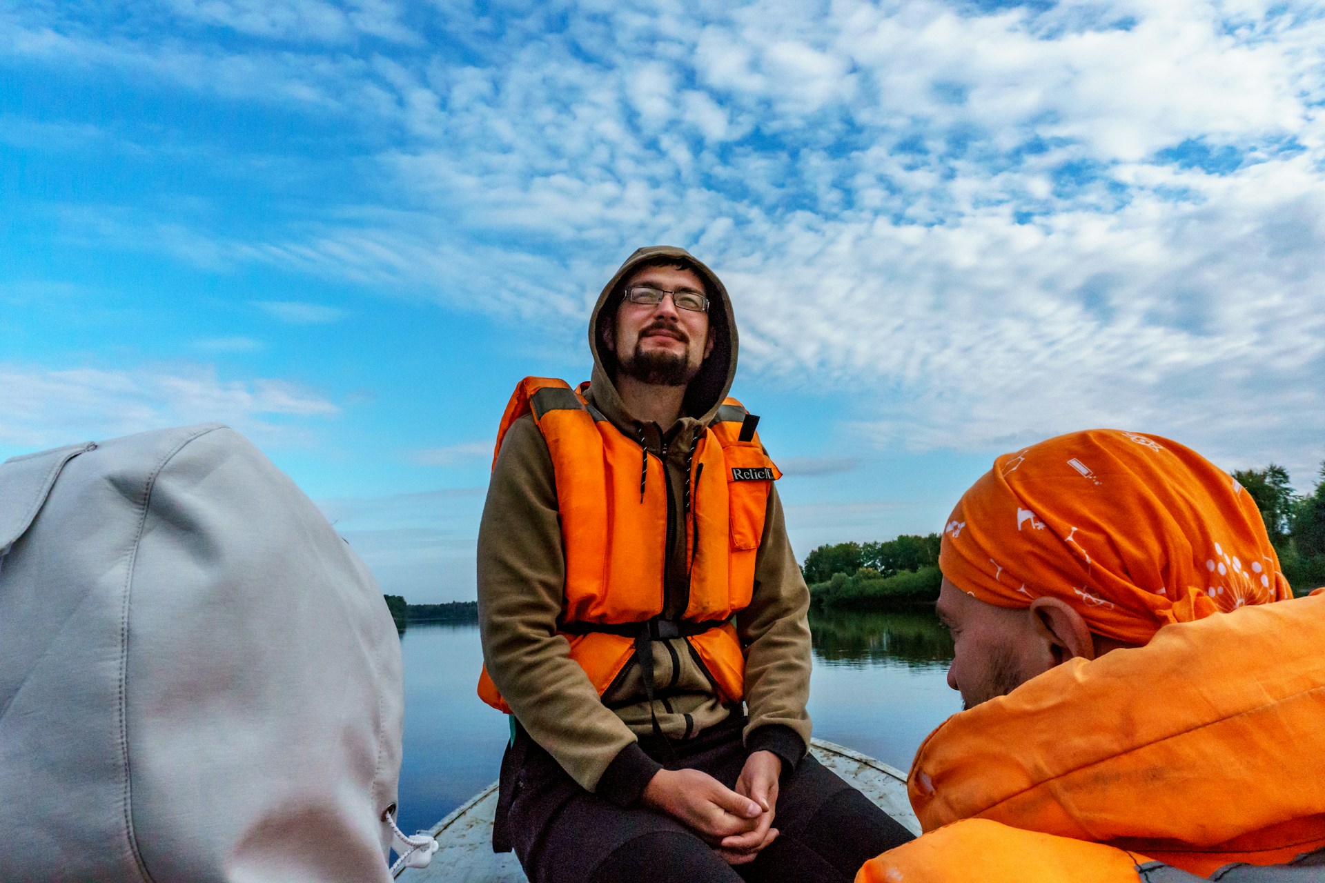 a man sitting in the prow of a boat wearing a life jacket