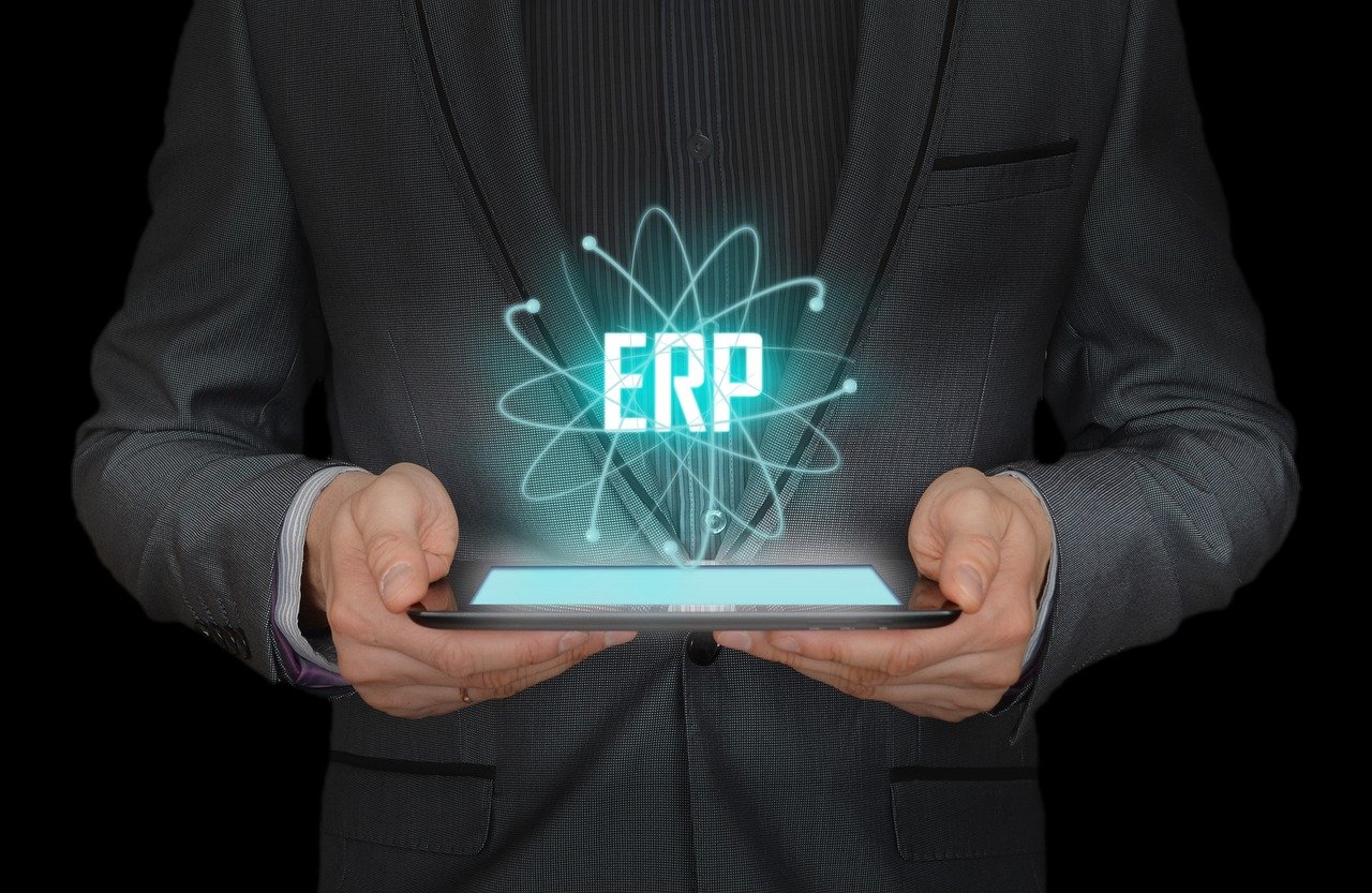 a business man holding a tablet PC with the acronym ERP hovering from it