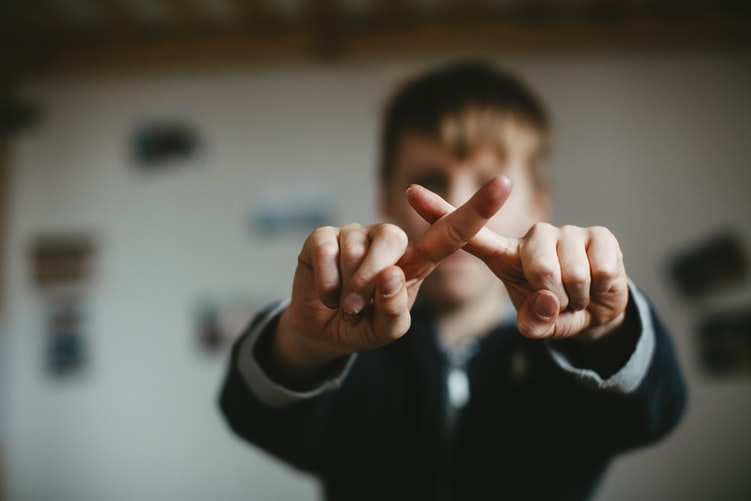 person crossing their fingers in a 'no' gesture