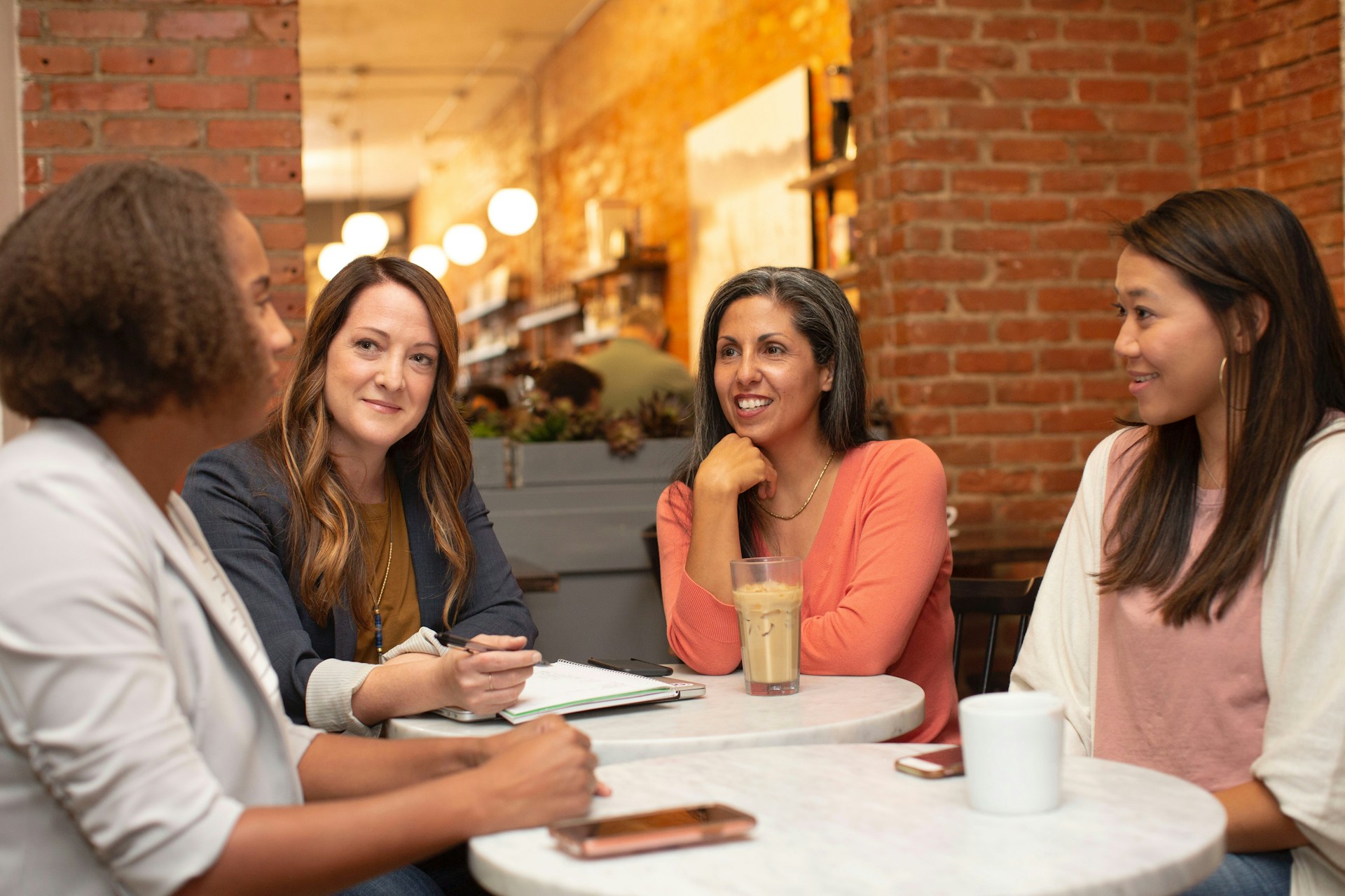 four female coworkers chatting around a table