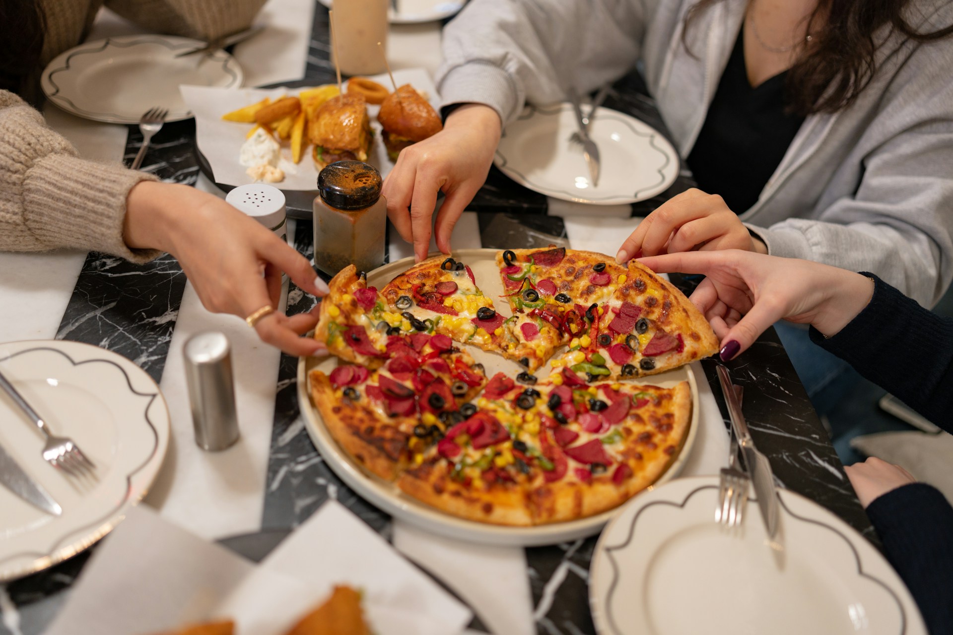 people sharing pizza in a restaurant 