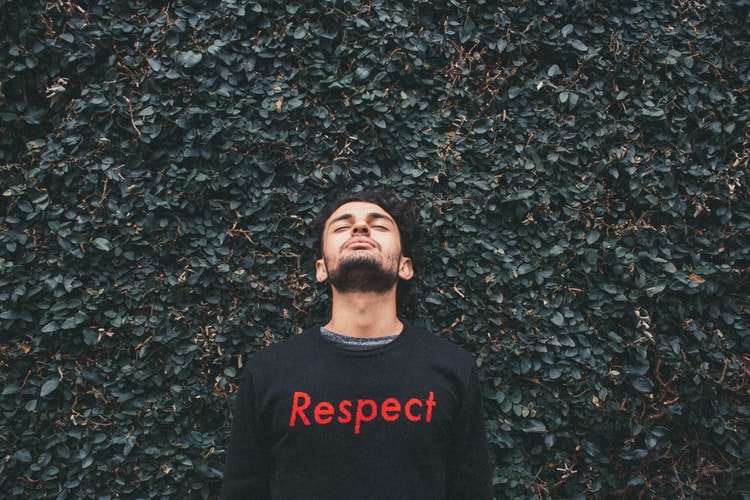 a man wearing a black top with the word 'respect' on the front