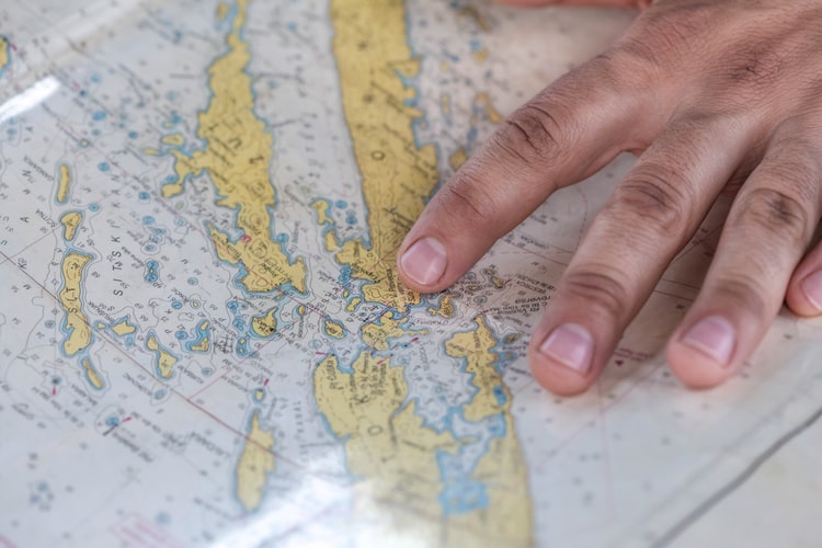 a hand pointing to a point on a map