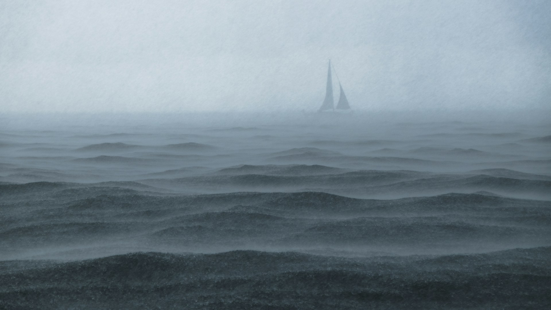 a sailboat dimly seen through the fog at sea