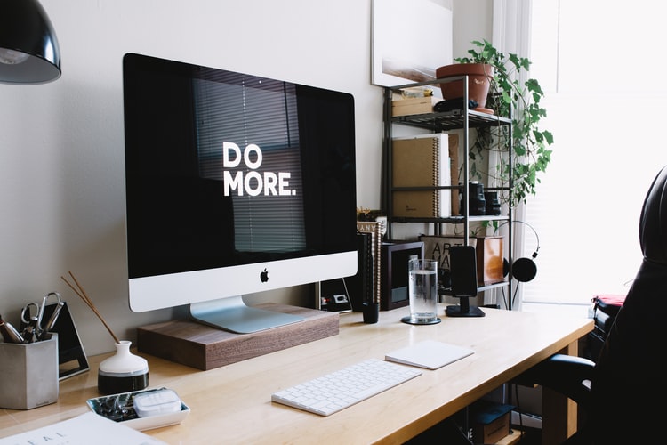 a computer monitor on a desk with the words 'do more' on screen