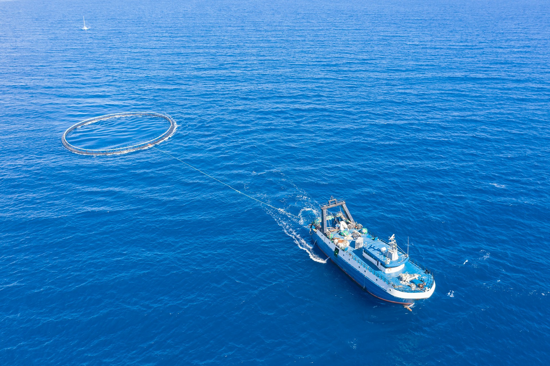 a fishing trawler dragging a circular net behind it