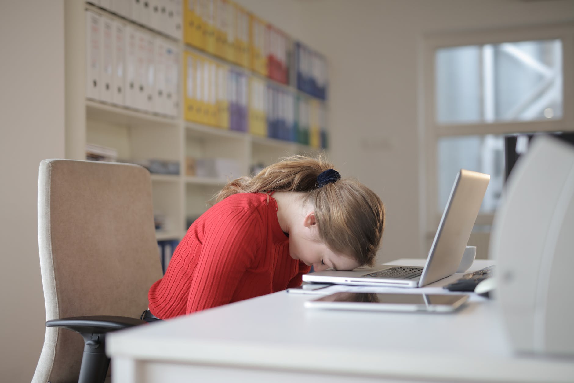 woman with her head on her desk in despair