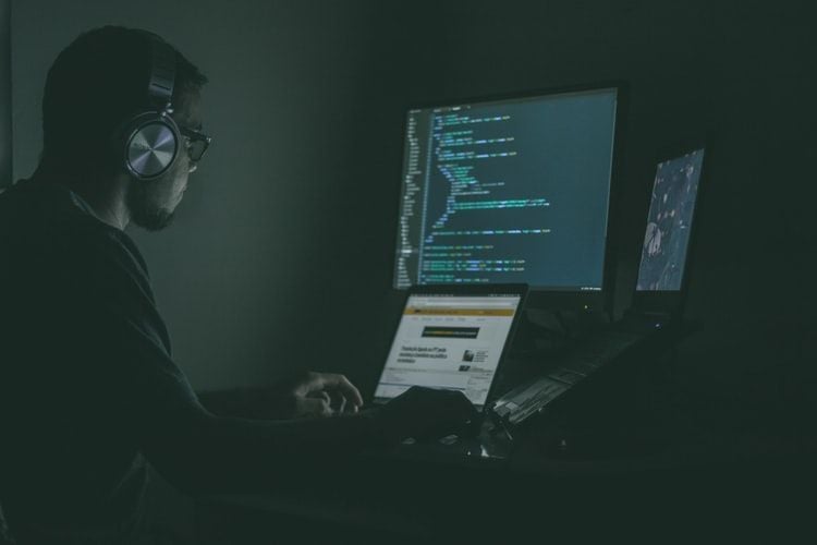 man in darkened room looking at laptop