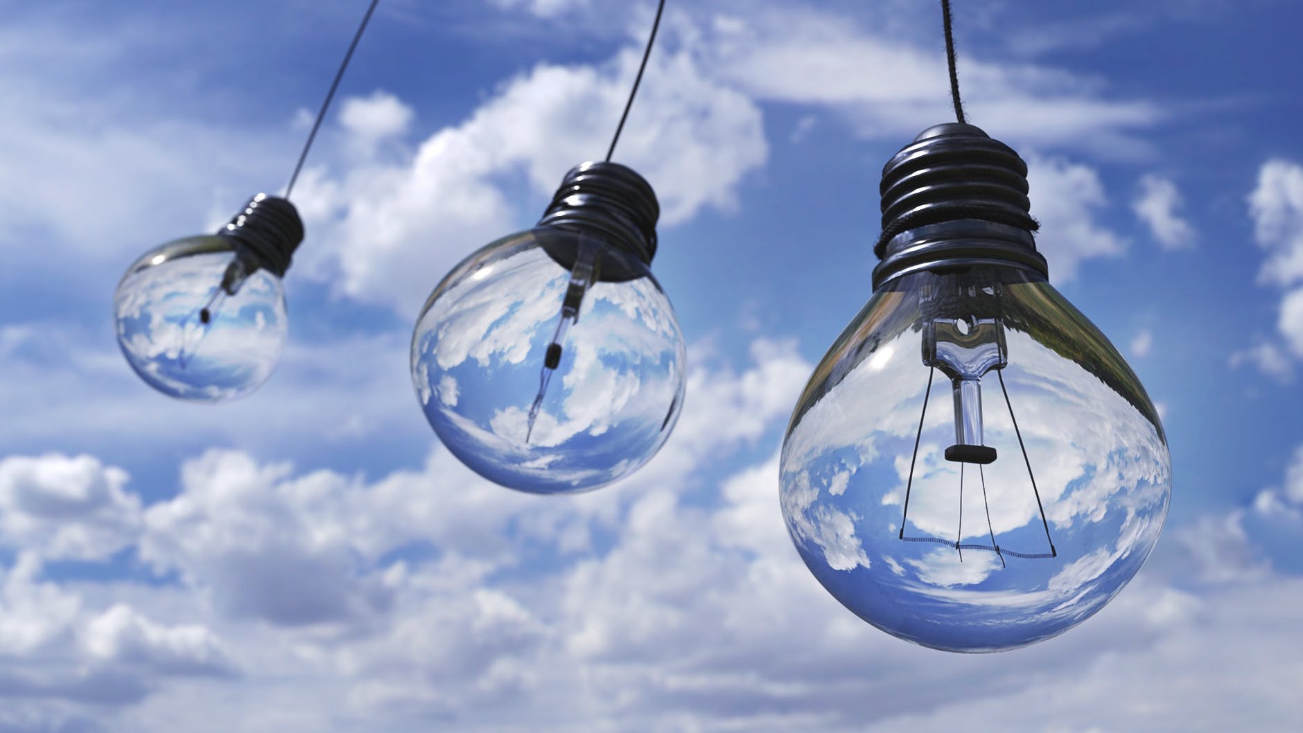 three lightbulbs hanging in front of a blue cloudy sky