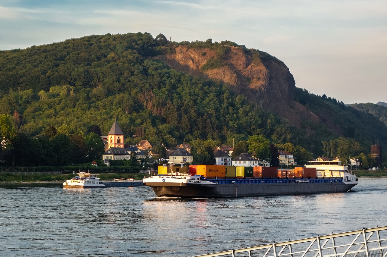 a cargo ship sailing past a church and hillside