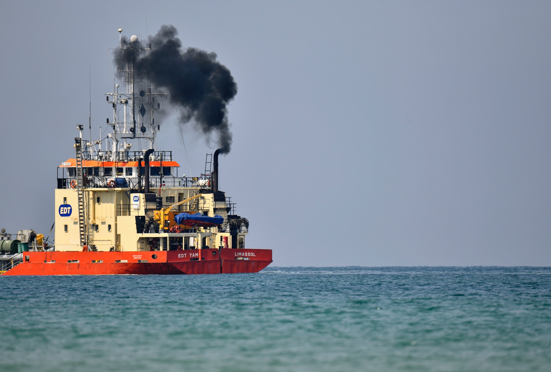 a dredger with black smoke coming out its funnel