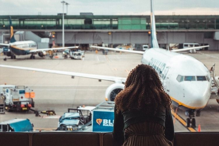 woman looking at airplane through window