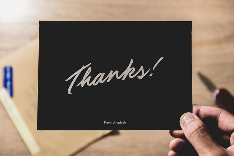 a hand holding a card saying thanks