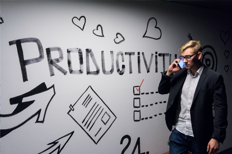 man standing next to a whiteboard with the word 'productivty' written on it