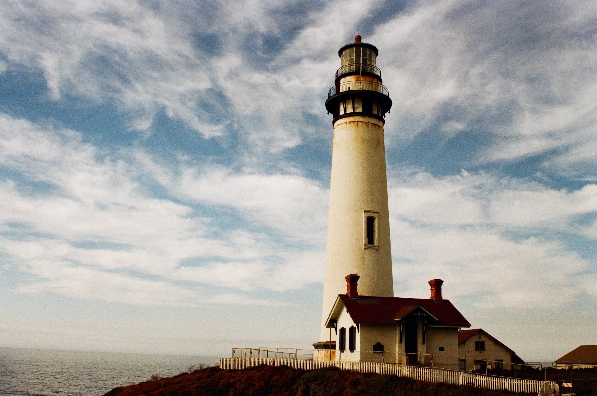 a white lighthouse on a cliff