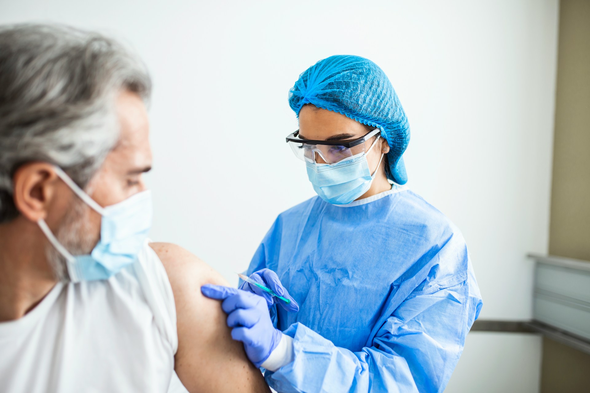 a healthcare professional injecting a man with a vaccine