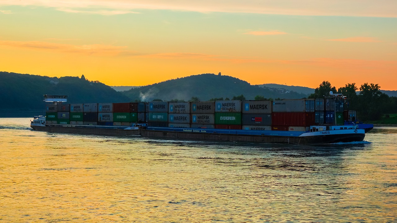 a cargo ship sailing near the coast at sunset