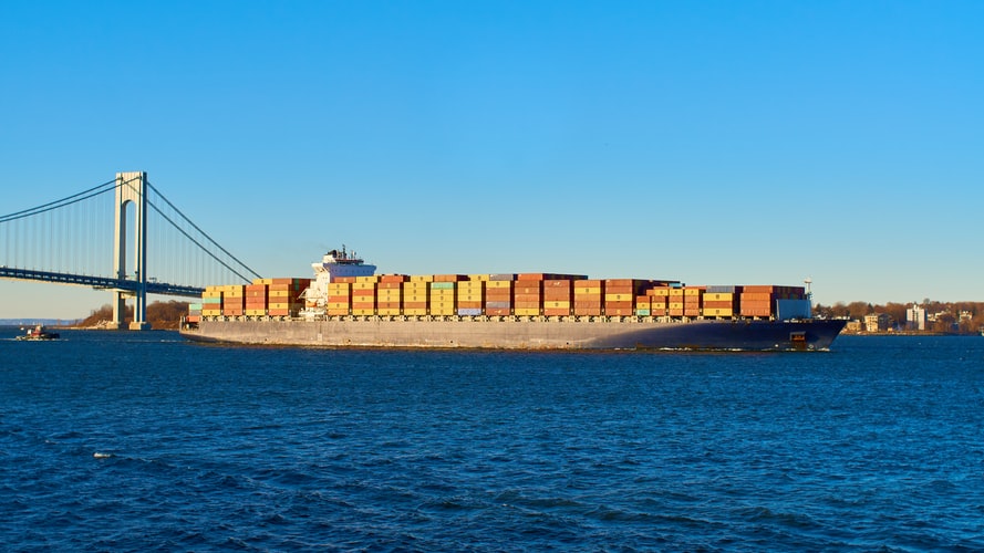 a container ship passing under a suspension bridge