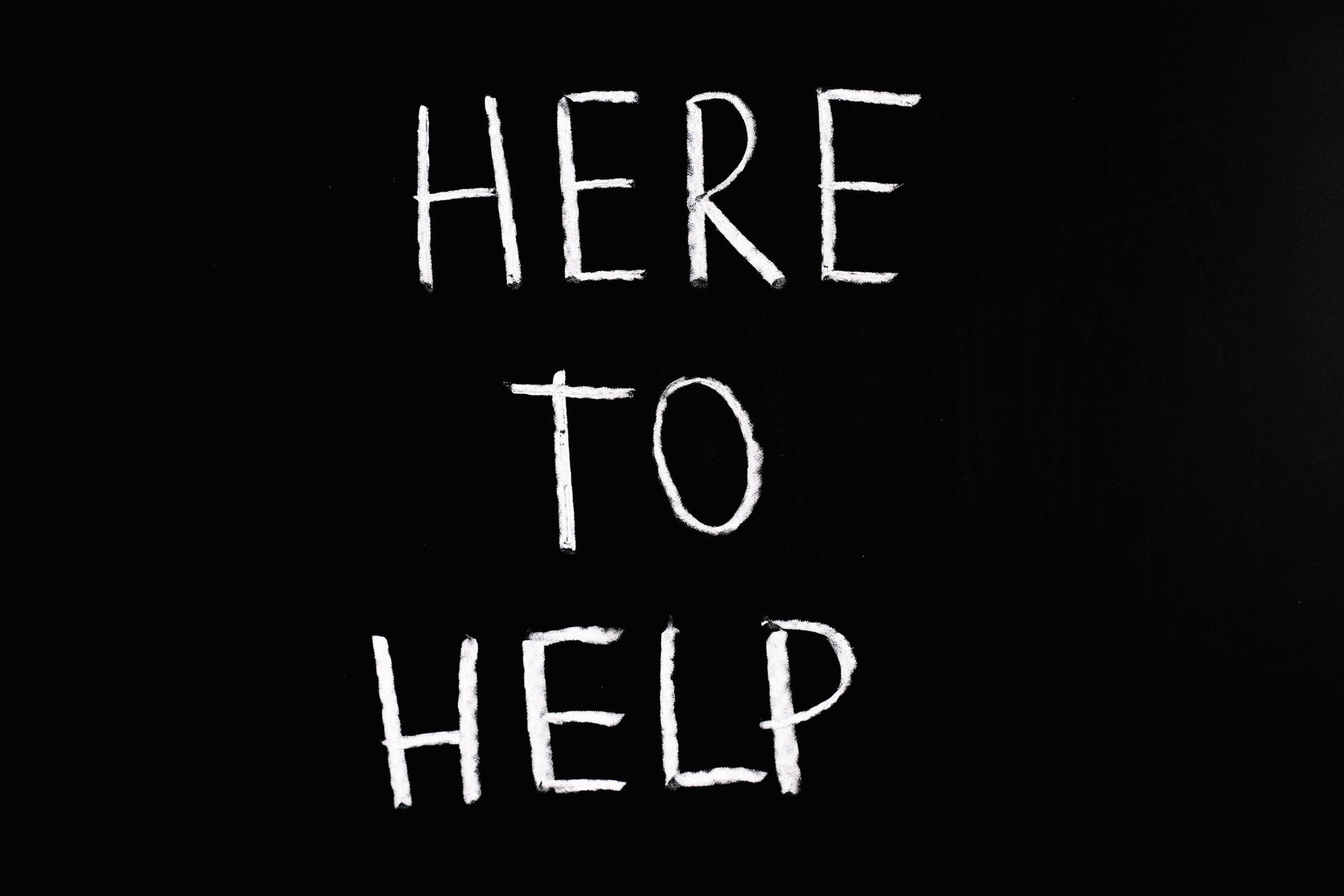 The words 'here to help' on a chalkboard